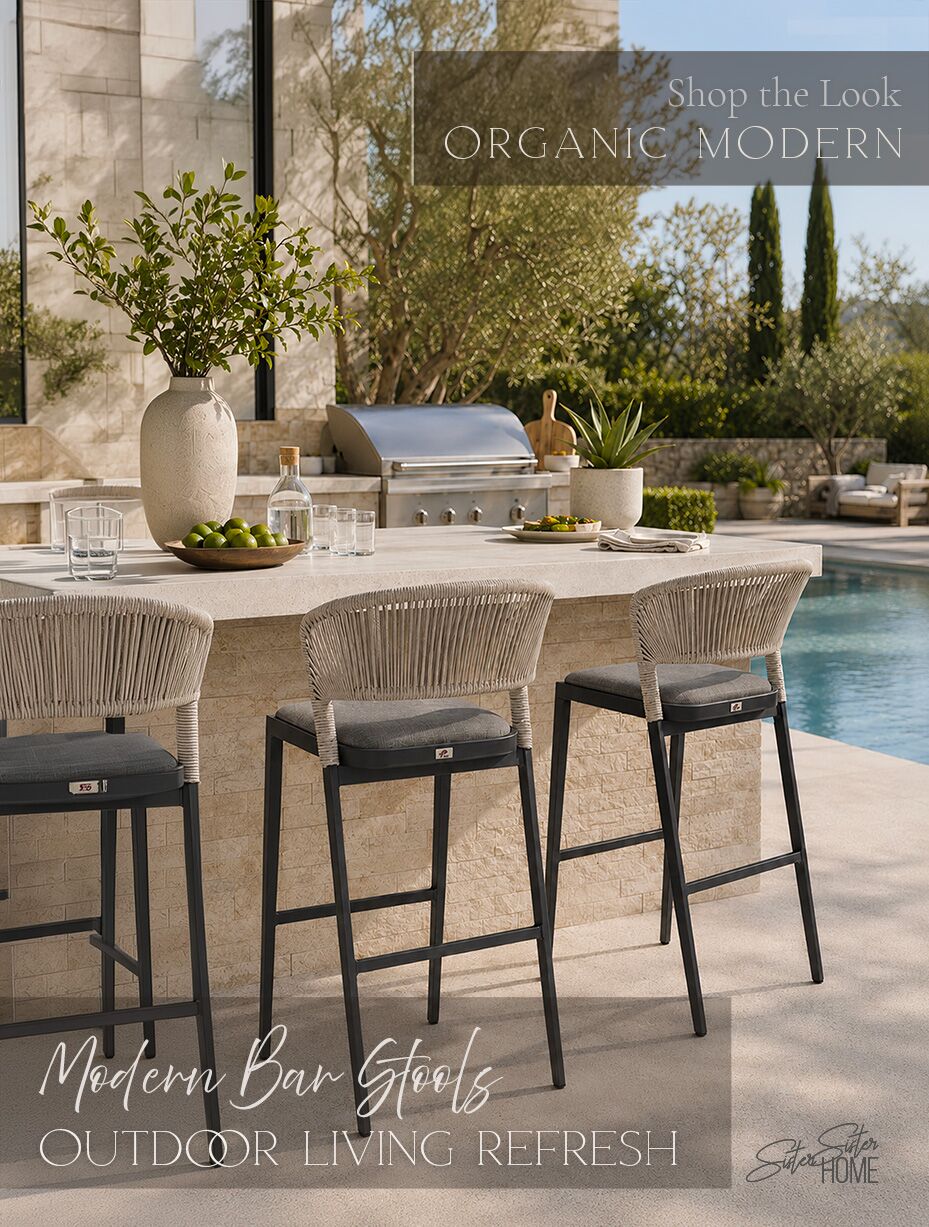 Modern outdoor kitchen with woven rattan bar stools, poolside seating, neutral stone finishes, greenery, and simple entertaining accents.